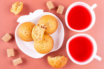 Homemade rice muffins with raisins on a white plate, two cups of raspberry tea, brown sugar on a pink background. Rice flour cupcakes. The concept of proper nutrition, breakfast, gluten-free diet.