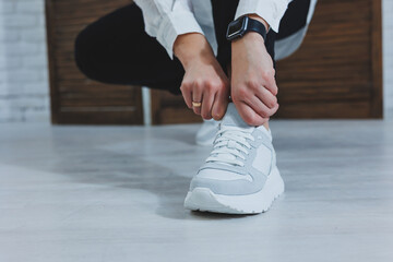 Beautiful women's shoes with legs, leather white sneakers, in the interior of a room or office, shoes for a woman, black trousers and white sneakers, casual and modern style, modern and trendy