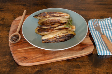 several endives braised in a dish on a wooden base