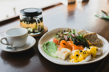 Light and hearty breakfast, brunch with scrambled eggs, toast on grain bread and smoked salmon and guacamole. Served with a mix of arugula and radish