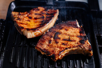Pork rib steak in sauce and spices fried in a grill pan. The process of cooking pork steak.