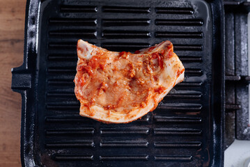 Pork rib steak in sauce and spices fried in a grill pan. The process of cooking pork steak.