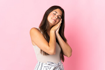 Young brazilian woman isolated on pink background making sleep gesture in dorable expression