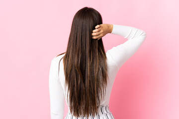 Young brazilian woman isolated on pink background in back position and thinking