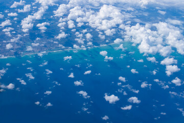 Fototapeta na wymiar view from an airplane through rare clouds to a resort town in the ocean