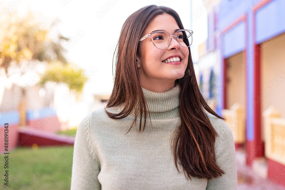 Wall mural Young Brazilian woman at outdoors With glasses with happy expression