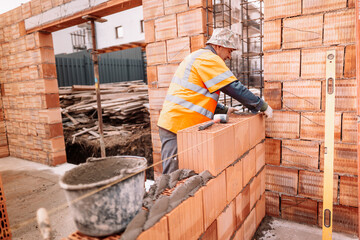 industrial details - Construction bricklayer worker building walls with bricks, mortar and putty knife