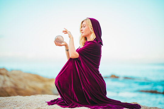 Woman in a Red hood with a crystal ball at the beach doing a ritual