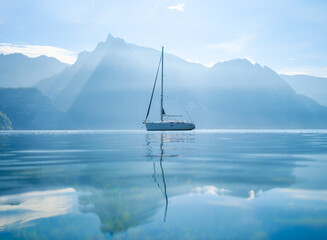 A yacht against the backdrop of the mountains in Switzerland. Calm water and bright sunny day. A...