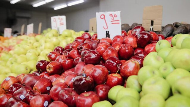 Tracking shot of different kind of ripe fruit on shelf in market. Red, yellow and green apples with price for them at Tel Aviv market, Israel