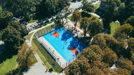 Aerial view of the blue stadium in the park, teenagers playing basketball