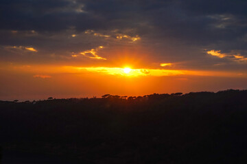 Filtering warm sun rays through the clouds at the sunset