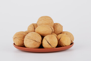 Many walnuts are lying on plates on a white background.