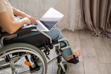 Obraz premium A woman in a wheelchair uses a laptop.