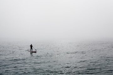 A man surfing in the fog on the sea