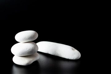 Stack of 3 white zen rocks piled up on a black background