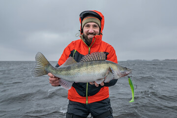 Success zander fishing. Happy fisherman with big walleye fish trophy at lake