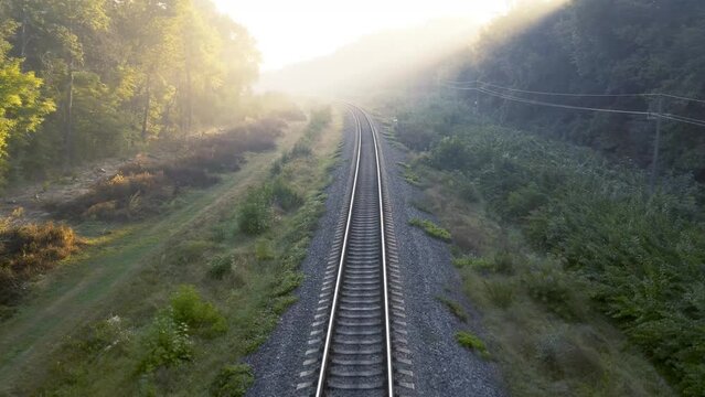 Morning sun rays through the fog on the railway tracks.
