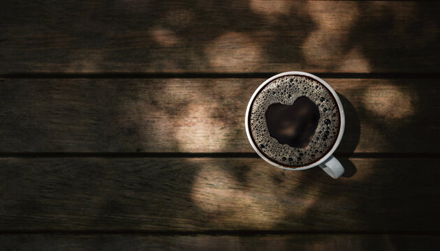 Love and Valentines Day Concept. Hot Black Espresso Coffee Cup on Wooden Table with a Heart Shape. Top View