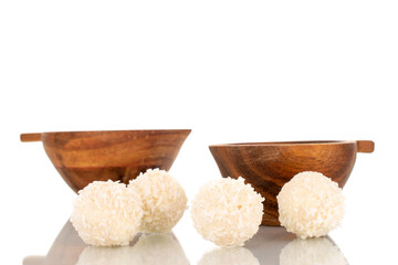 Some sweet coconut candy with two wooden cups, macro, isolated on a white background.