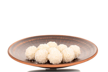 A few sweet coconut candies on a clay plate, macro, isolated on a white background.