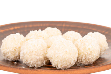 A few sweet coconut candies on a clay plate, macro, isolated on a white background.
