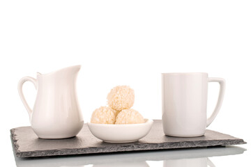 Some sweet candy with coconut shavings with white ceramic dishes on a slate stone, macro, isolated on a white background.