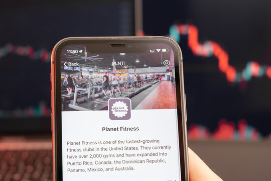 Planet Fitness Stock Price Decrease On The Trading Market With Downtrend Line Graph Bar Chart On The Background. Man Holding A Mobile Phone With Company Logo, February 2022, San Francisco, USA. 