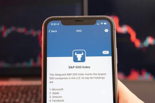 SP 500 Index stock price decrease on the trading market with downtrend line graph bar chart on the background. Man holding a mobile phone with company logo, February 2022, San Francisco, USA. 
