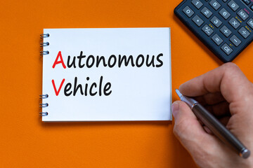AV autonomous vehicle symbol. Concept words AV autonomous vehicle on white note on a beautiful orange background. Businessman hand. Business technology AV autonomous vehicle concept. Copy space.