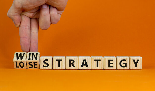 Win-lose strategy symbol. Businessman turns wooden cubes and changes words lose strategy to win strategy. Beautiful orange table, orange background. Business, win-lose strategy concept. Copy space.