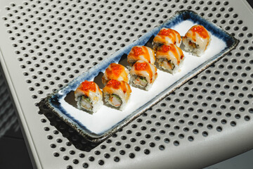 Sushi rolls with eel, shrimp, cucumber and cream cheese, decorated with red caviar. Hard light, deep shadow