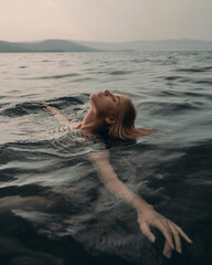 Girl swims relaxed in a beautiful mountain lake