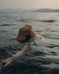 Girl swims relaxed in a beautiful mountain lake