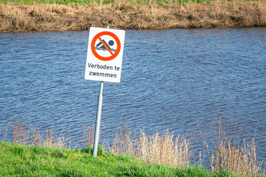 Sign reading "Forbidden to swim" (Dutch: verboden te zwemmen) near a river