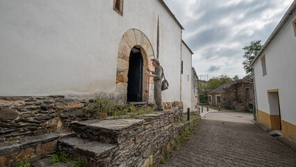 Fototapeta na wymiar Pilgrim walking on the Camino de Santiago, at the door of the church. Way of St James