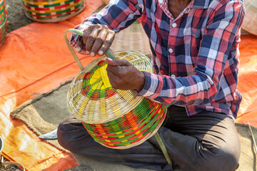 Rural Indian craftsman working on a handmade basket for sale at a handicraft fair at Kolkata, India