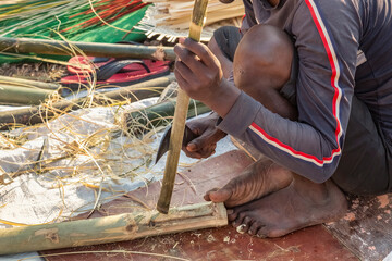 Rural craftsman cutting bamboo sticks for creating furniture items at a handicraft fair at Kolkata, India