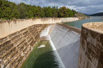 Water flows out of the reservoir. The dam is overflowing as a result of heavy rains. Excess water...