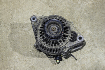 Old dirty car generator on a gray background close-up. Car parts
