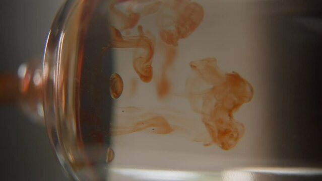 Perfumer pouring drops of oily scent into perfume in a glass bottle. Process of creating exquisite odour smell using orange essence and perfume extrait fragrance. Vertical video 9x16. Macro shot.