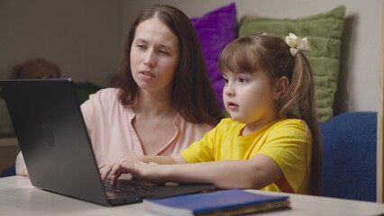mom explains kid school topic lesson. happy family. helping my daughter with homeschooling. little student studies laptop with her mother. teacher helps kid understand topic lesson computer. teamwork.
