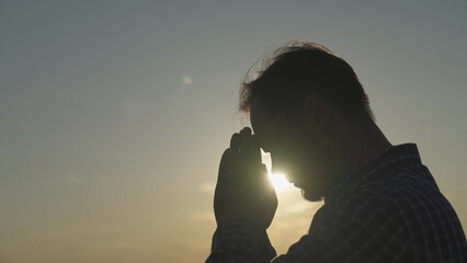 man praying at sunset, asking heaven for help and support, spiritual man contemplating, the concept...