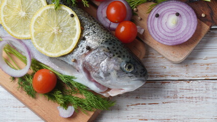 Fresh trout on a table with lemon, pepper and dill. Tasty fish ready for cooking. Healthy seafood and dieting concept.