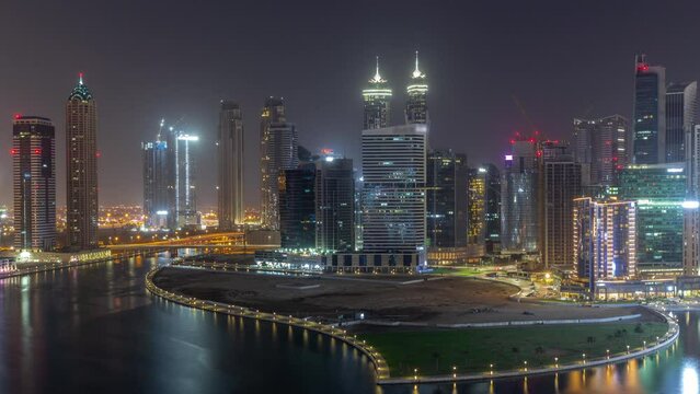 Cityscape of skyscrapers in Dubai Business Bay with water canal aerial all night timelapse