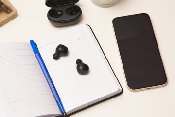 Blank notebook, phone and earphones on a office desk