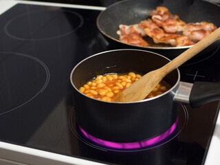 Beans and Bacon cooking in pans and pots wooden spoon