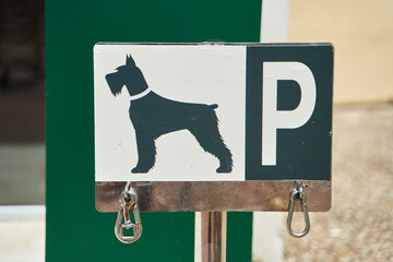 Designated dog parking sign. Place for bind dogs waiting for owners outside, with rings for...