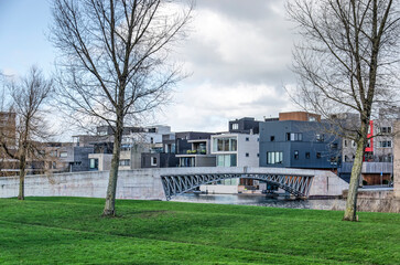 Obraz premium Amsterdam, The Netherlands, February 11, 2022: concrete pedestrian bridge across a canal lined with cubist modern housing