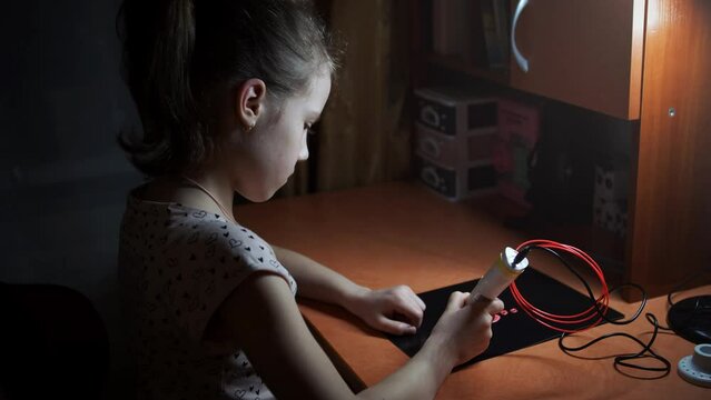 A girl draws a heart with a 3D pen. The daughter creates a beautiful pink keychain as a gift for mom on mother's day or for dad on father's day. close-up work 3d pens.